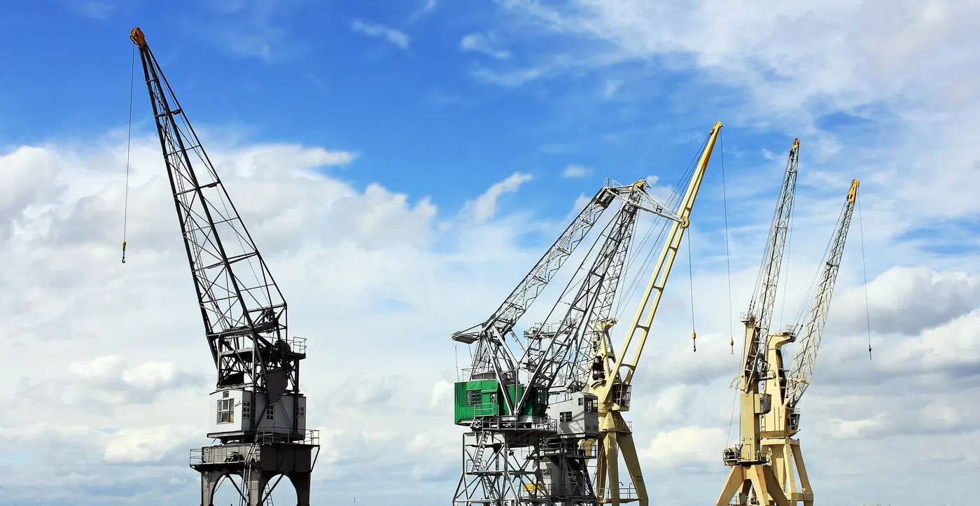 Mobile crane lifting steel structure at extended boom radius on a UAE construction site
